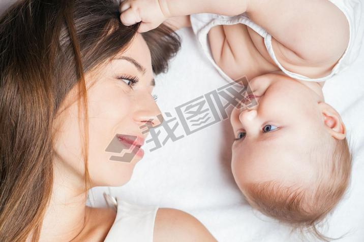 Happy mother with a baby lying on a white bed
