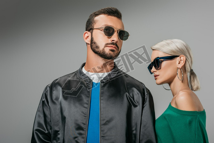 fashionable couple posing in sunglasses, isolated on grey