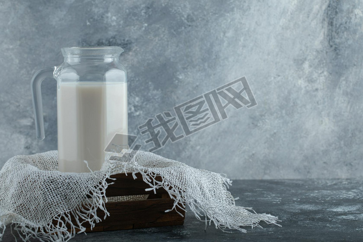 Glass jug of milk in wooden box with burlap