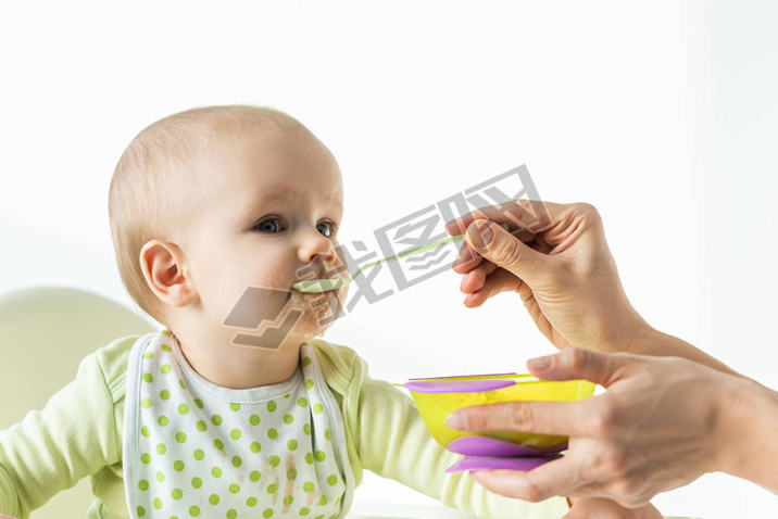 Mother feeding baby son with baby nutrition on white background