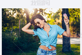 young beautiful short blue hair hipster woman with headphones music in the park. ice cream