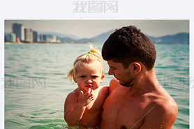 european young father holds iling little daughter in shallow s