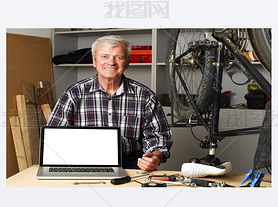 senior bike shop owner behind laptop