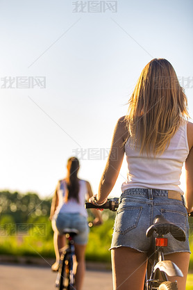 Young women on bikes, rear view