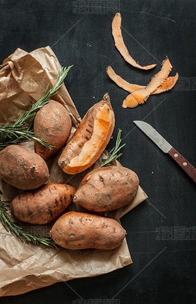 Peeling sweet potatoes with knife on black chalkboard