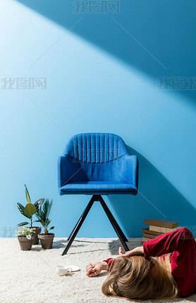 woman lying on floor with cup of coffee in front of blue wall