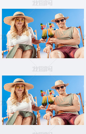 Young attractive couple toasting with cocktails resting in deck chairs on blue background