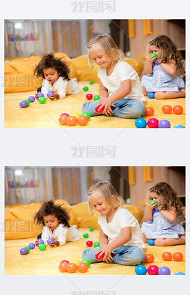 adorable multicultural kids playing with colored balls on floor in kindergarten