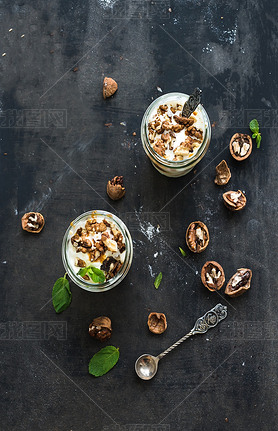 Walnut and salted caramel ice-cream in glass jars with fresh mint over dark grunge backdrop, top vie