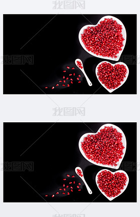 Two white heart shaped plates full of fresh ripe juicy pomegranate seeds, little spoon, whole fruit 