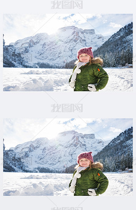 Happy child in green coat standing in front of snowy mountains