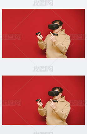Teen gamer in a VR helmet stands on a red background with controls in his hands and plays virtual re