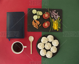 top view of khinkali, vegetables, coffee, notepad, spoon on the table