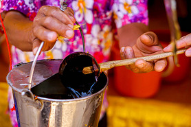 Closeup hand of people holding coconut shell ladle scoop water from the tank to The bathing of the r