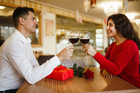 Young couple having a romantic dinner and toasting with cups of red wine. Sweet couple celebrate the