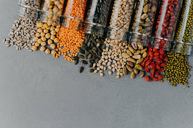 Healthy products in glass jars. Organic grains in containers on grey background. Blank space at bott