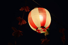 Upward shot of a red and white Japanese lantern, dark background 