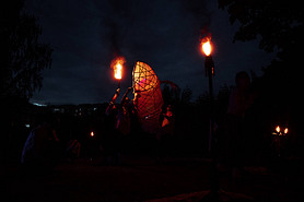 a dangerous and beautiful fireshow in the dark. artists in costumes of mythological creatures hold b