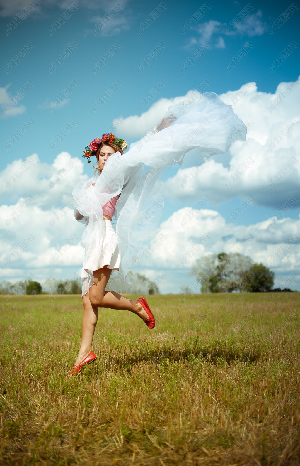 Girl in flower wreath with white shawl dancing on meadow