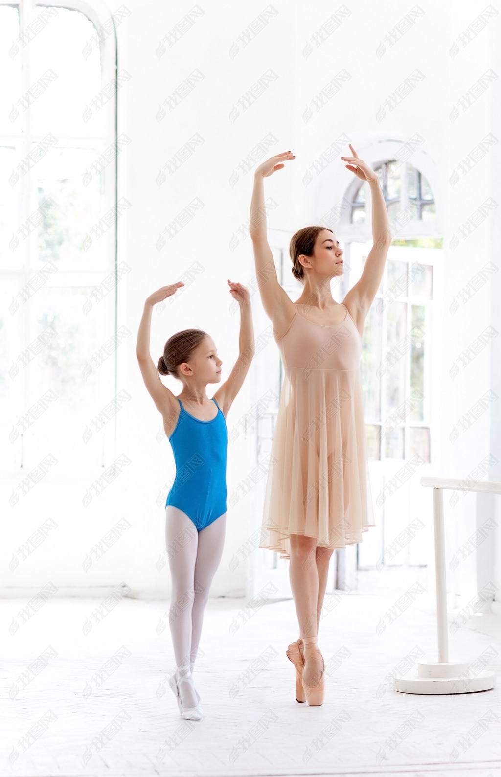 The little ballerina posing at ballet barre with personal teacher in dance studio