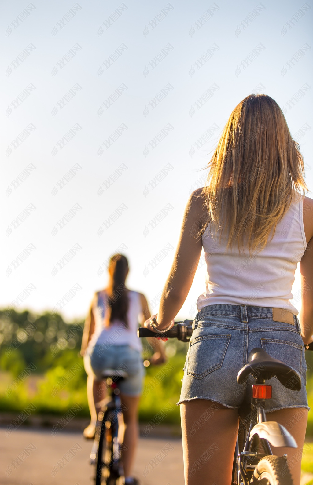 Young women on bikes, rear view