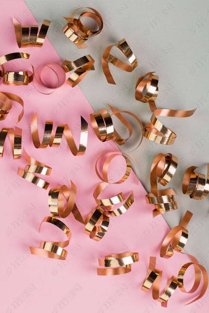 Christmas and New Year's Day festive decoration, golden ribbons on pink and gray background. Copy sp