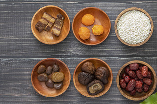 Bowls with dried fruits and white rice on a wooden surface.