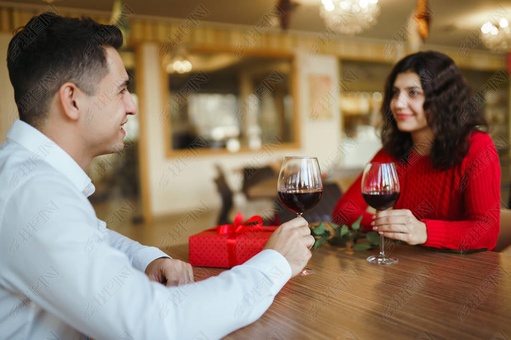 Young couple having a romantic dinner and toasting with cups of red wine. Sweet couple celebrate the