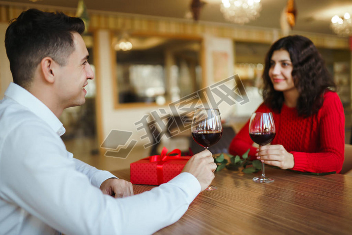 Young couple having a romantic dinner and toasting with cups of red wine. Sweet couple celebrate the