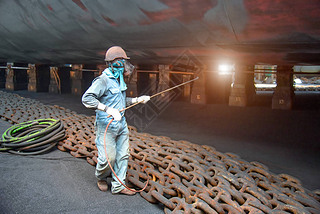 worker, paint man, working for repainting after sand blasting of the bottom layer of the commercial