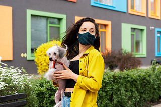 城市里，一个戴着黑色医疗面罩的漂亮姑娘和一只中国狗儿一起散步
