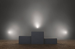 An empty classic winners podium on sand backlit by dramatic spot lights on a dark moody background -