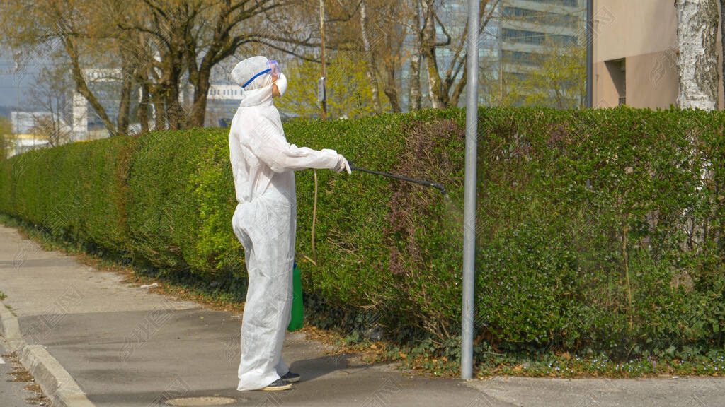 Virologist disinfects a street lamp and sidewalk during covid-19 outbreak.