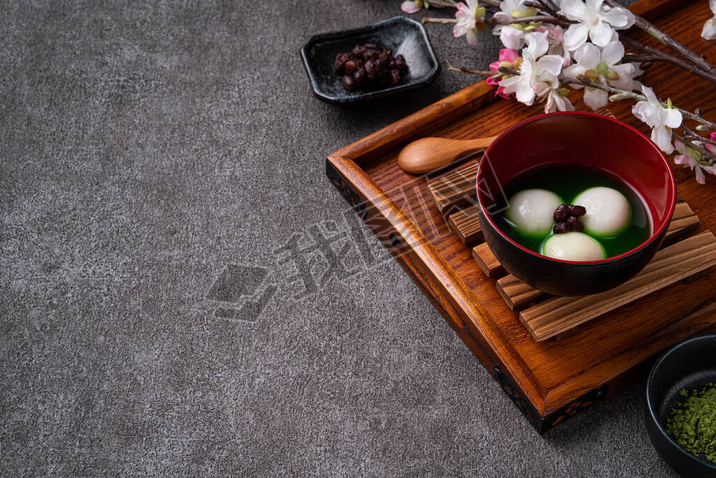 Close up of matcha big tangyuan (tang yuan) with sweet matcha soup in a bowl on wooden table backgro