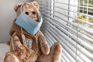 A teddy bear in a medical mask with pills and a thermometer