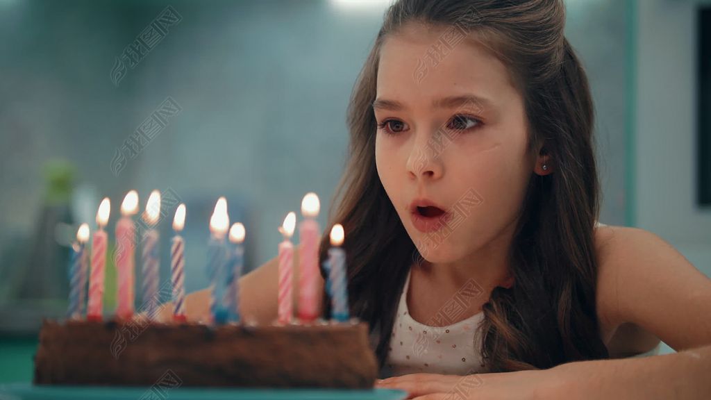 慢动作中吹蜡烛的女孩的肖像.儿童生日快乐概念