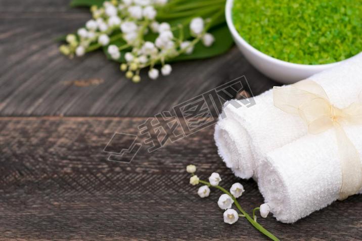 Natural green sea salt and towel for bath and spa on a wooden bo