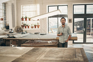 designer standing in workshop with cup of coffee