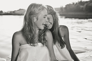 Black and white photography of 2 beautiful princess young ladies in white dresses on summer water ou