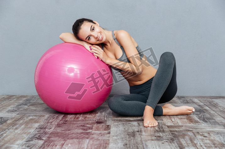 Young beautiful fitness girl with pink ball isolated on grey