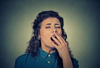 sleepy young woman with wide open mouth yawning eyes closed