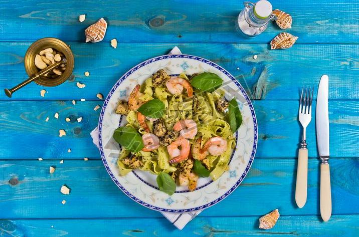 Tagliatelle pasta with shrimps, nuts and chicken on wooden table