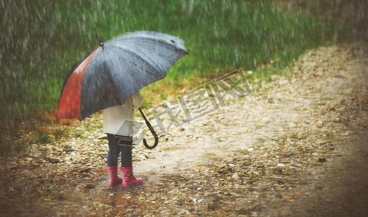 happy baby girl with  umbrella in the rain runs through