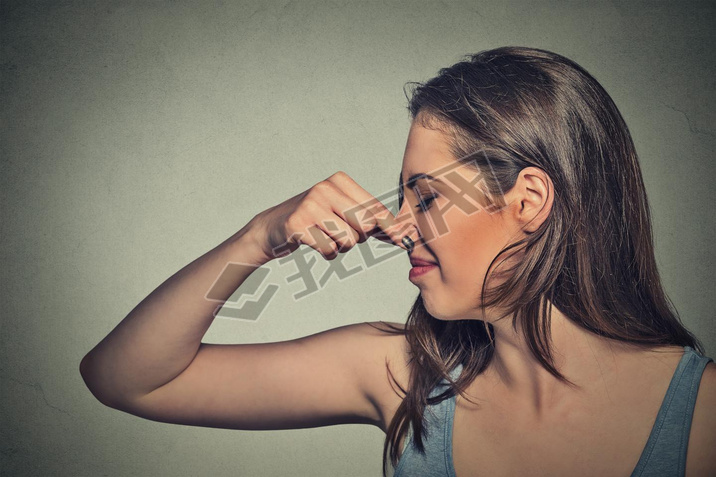 woman pinches nose with fingers looks with disgust away something stinks