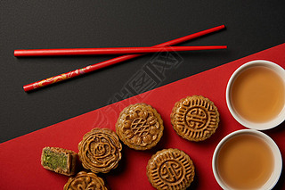 红色和黑色背景上的传统中国月饼与筷子的顶部视图