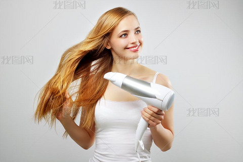 美丽的微笑女孩干燥用吹风机吹干头发