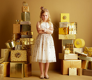 Full length portrait of furious young girl in beige fit and flare dress and a little crown on head s