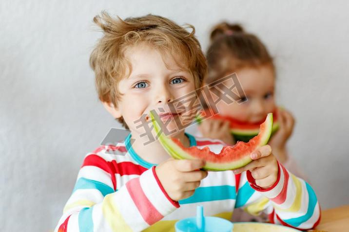 Little kid boy and girl eating healthy food watermelon