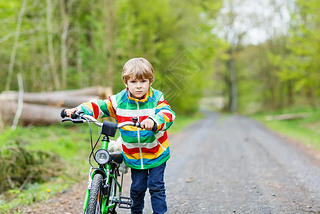 Little kid boy riding on a bike in forest