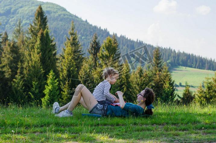 Young woman and a child resting on a green glade